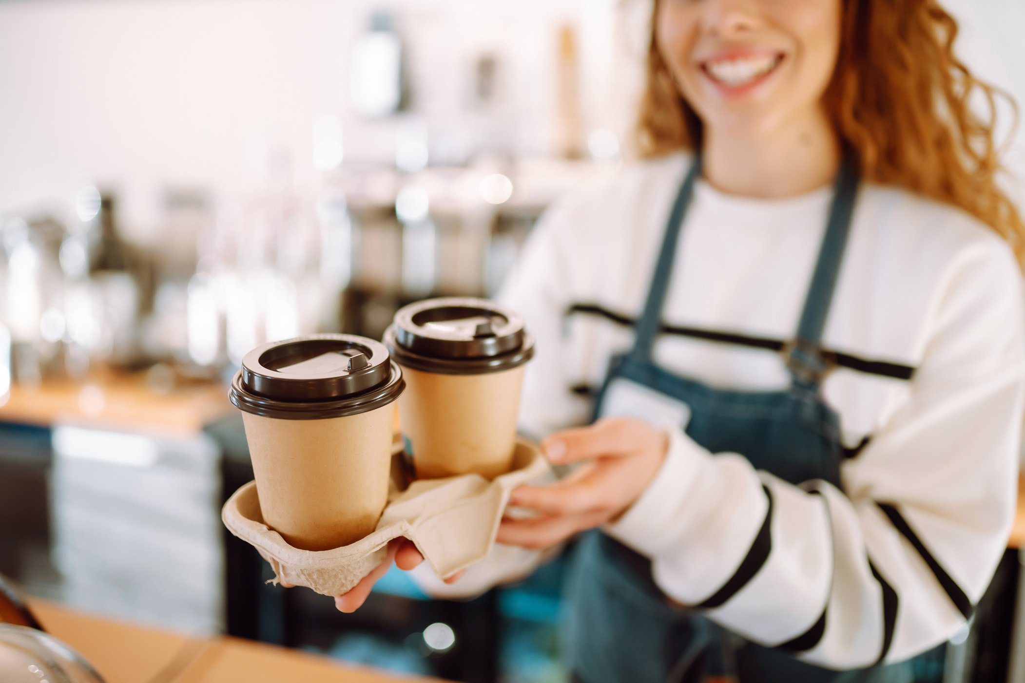 Take-away coffee. Barista girl holding take away coffee at the cafe shop. Takeaway food.